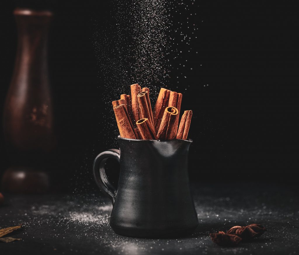 Close-up of cinnamon sticks in a pitcher with sugar dust, symbolizing how cinnamon helps stabilize blood sugar levels.