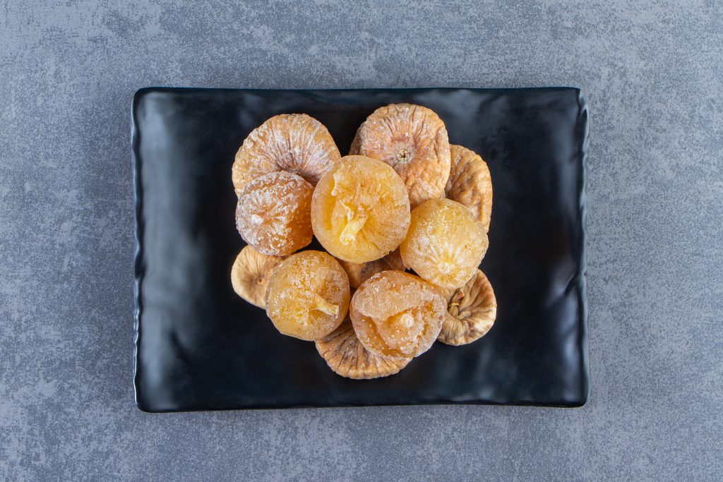 Top view of dried figs on a black plate, a healthy, high-calorie fruit for weight gain.