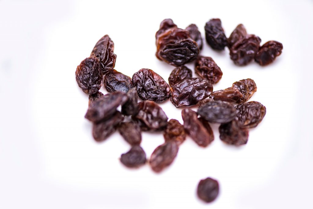 Dark brown raisins scattered on a white surface, a simple way to boost your calorie intake.