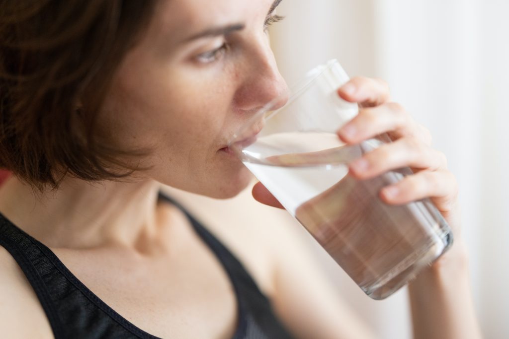 Close-up of a woman drinking water, highlighting how hydration helps increase calorie burning and supports metabolism.