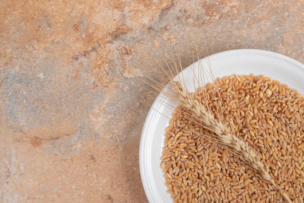 A white bowl of brown rice and wheat stalk, rich in selenium, which protects cells and supports the body's defense system.