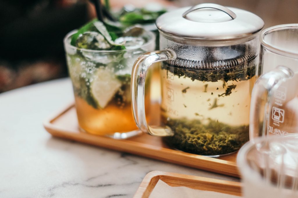 Teapot with green tea leaves and iced tea with mint, showcasing flavonoid-rich green and black teas packed with antioxidants.