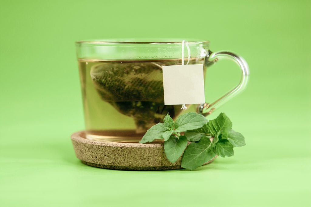 A glass mug of green tea garnished with fresh mint, highlighting its role in supporting weight loss.