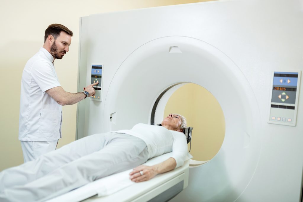 MRI technician adjusting the machine as the patient lies on the table for imaging.
