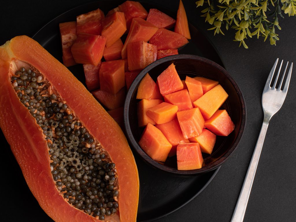 Fresh sliced papaya, halved and cubed in a bowl, showcasing a natural immunity booster on a plate.