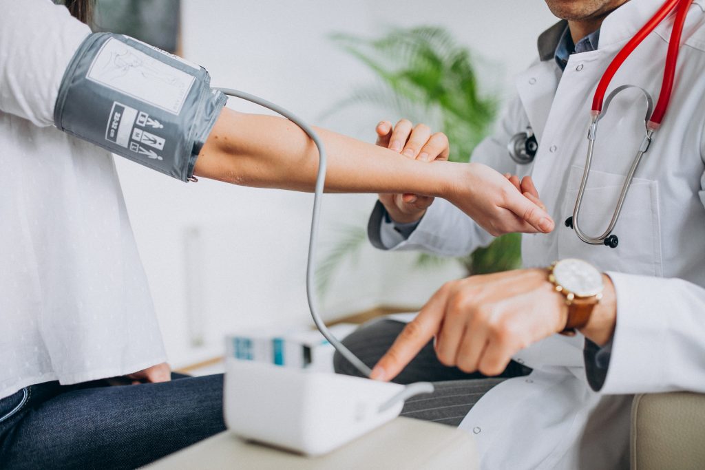 Doctor measuring blood pressure with a stethoscope, illustrating vitamin D&rsquo;s multiple roles in overall health.