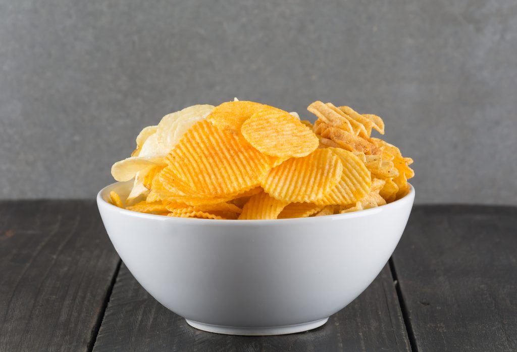 Potato chips in a bowl serve as a reminder that dietary choices impact period pain and PMS relief.
