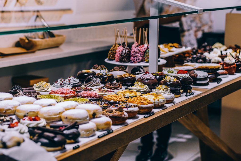 Display of sweet pastries and donuts, emphasizing sugar's role in obesity, high blood pressure, and diabetes risks for kidney disease.