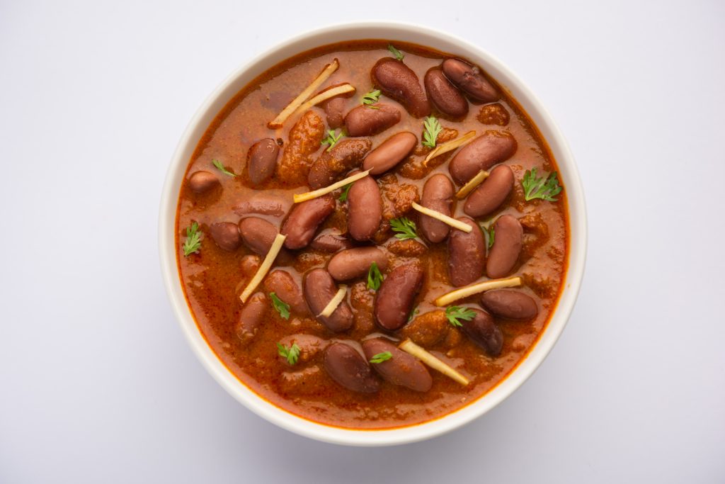 A bowl of rajma curry with garnish,highlighting the benefits of choosing tomato-based gravies.