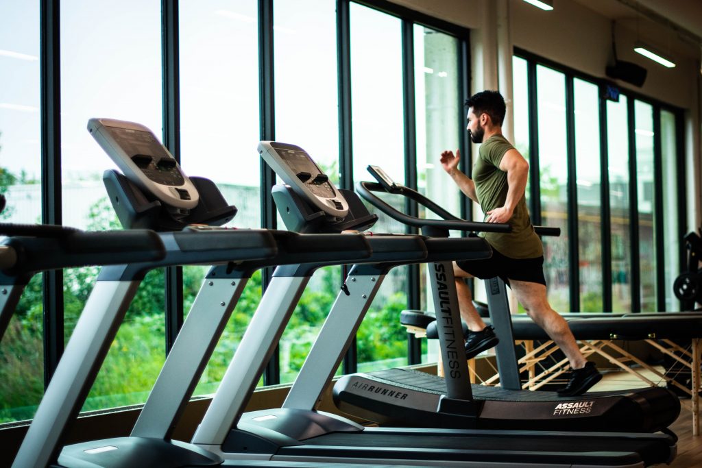 A man running on a treadmill in the gym, highlighting how cardiovascular exercise boosts overall health and fitness.