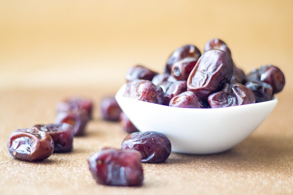 Bowl of dates and scattered dates, a delicious and healthy option for weight gain.