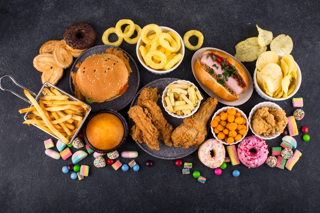 Burgers, fried chicken, fries, and candies on display, reflecting processed food&rsquo;s impact on health and well-being.
