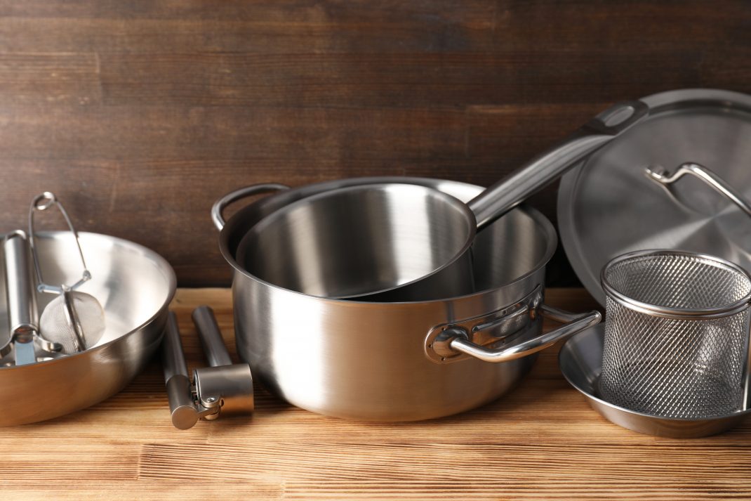 A stainless steel cookware set placed on a wooden countertop, showing the impact of cookware on food preparation.
