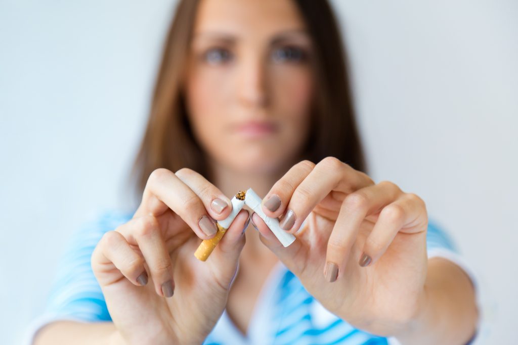 Young woman breaking a cigarette, symbolizing the fight against tobacco as a leading cause of disease.
