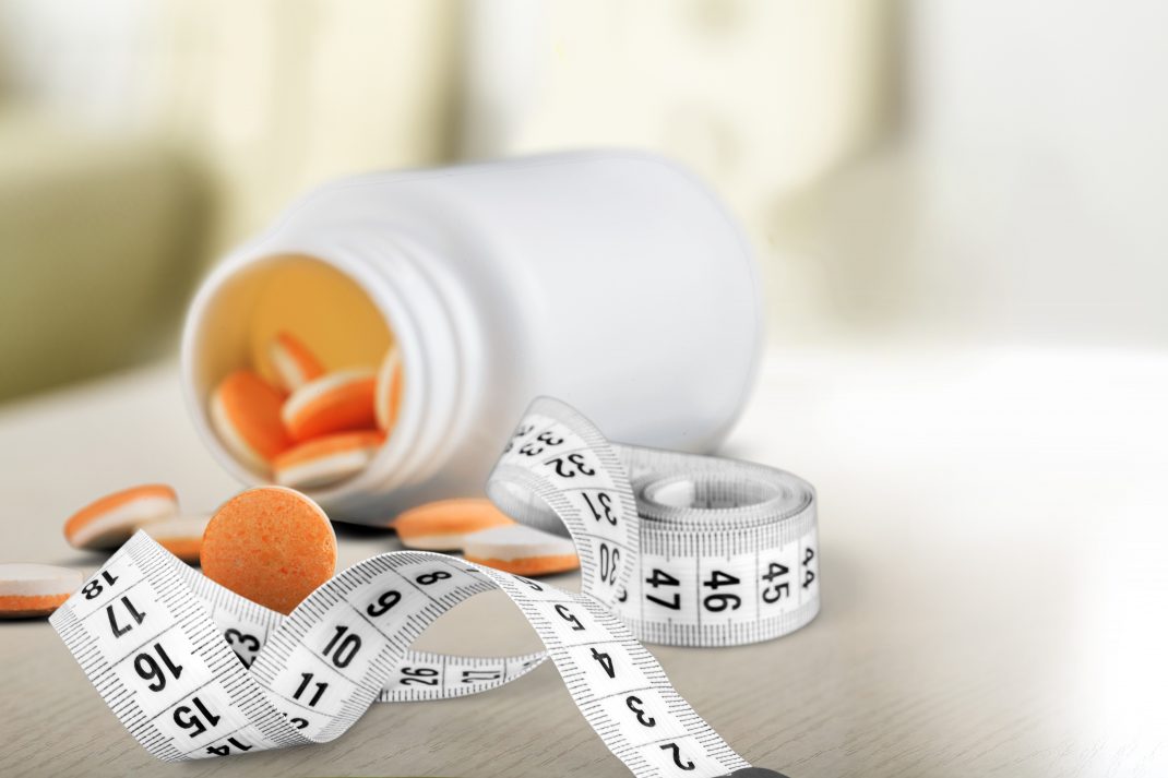 A picture of weight loss supplements alongside a measuring tape.
