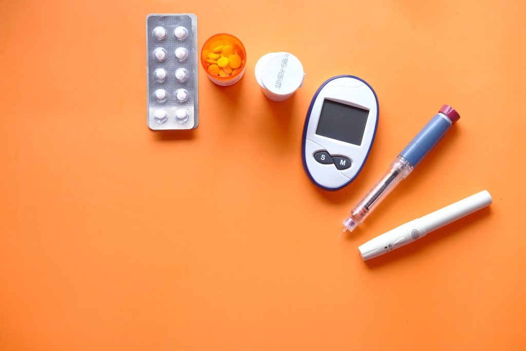 Diabetes tools like a glucose meter, insulin pen, and pill bottles, highlighting the Mediterranean diet’s role in preventing type 2 diabetes.