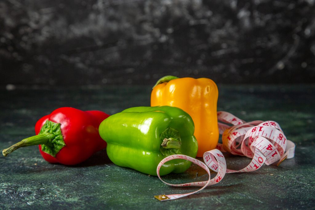 Red, green, and yellow bell peppers with a measuring tape, packed with vitamin C and unique health benefits.