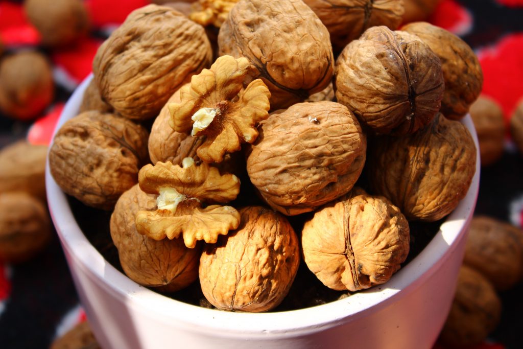 A bowl of peeled walnuts and shelled walnuts, helping to reduce blood pressure, improve vessel function, and lower inflammation.