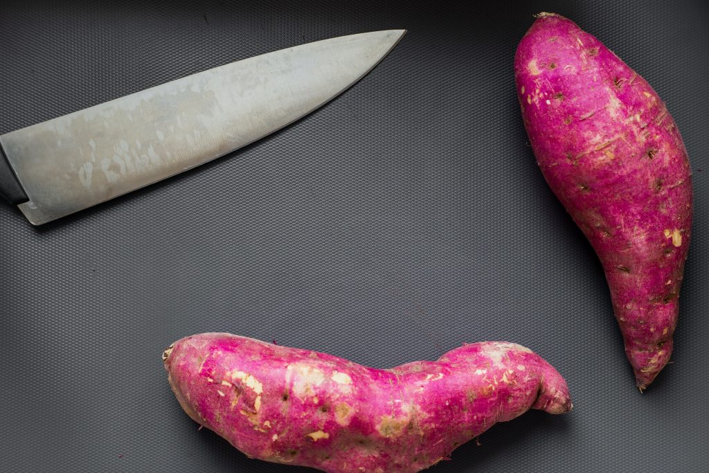 Top view of a red sweet potato and knife, a potassium-rich food known for its gut health benefits.