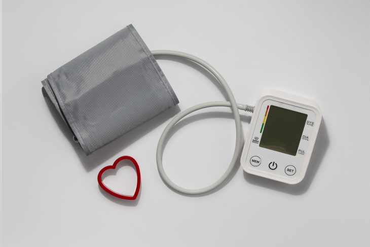 Image of Blood pressure gauge with cuff and monitor connected with a tube with heart symbol near it.