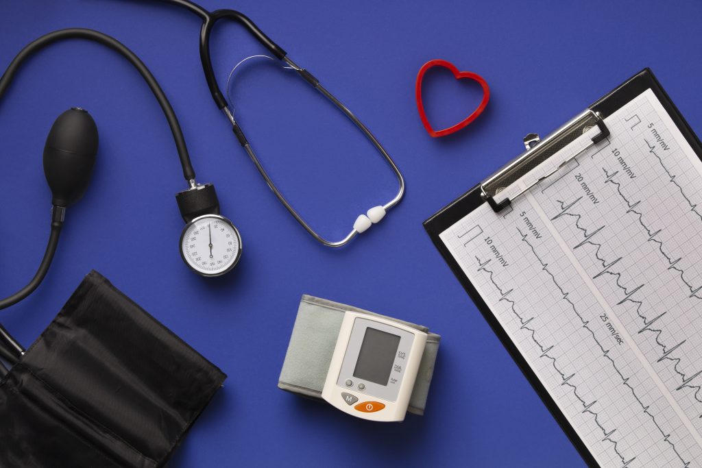 Blood pressure cuff, stethoscope, heart-shaped object, and ECG printout, highlighting the importance of a preventive health checkup.
