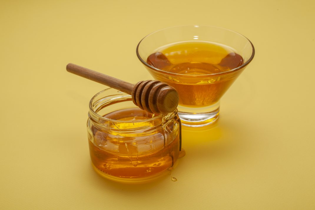 Bottle of honey with a dipper and bowl, providing effective health and medical advantages.