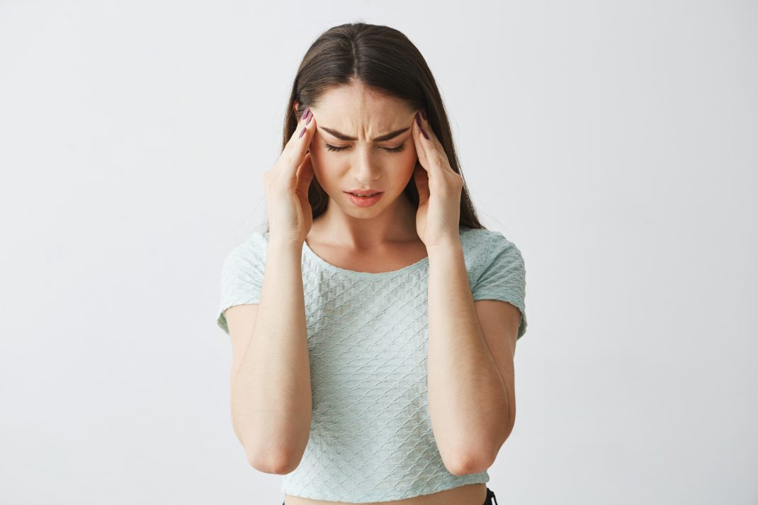 Woman holding her head in pain, indicating possible health issues from Vitamin D deficiency.