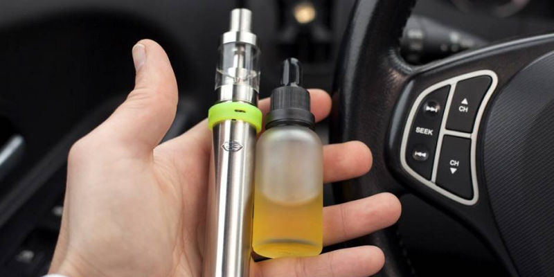 A person holding a vape juice bottle and a smoking device.