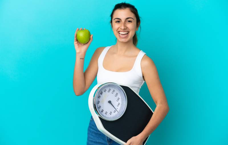A woman with an apple and scale, promoting a balanced diet.
