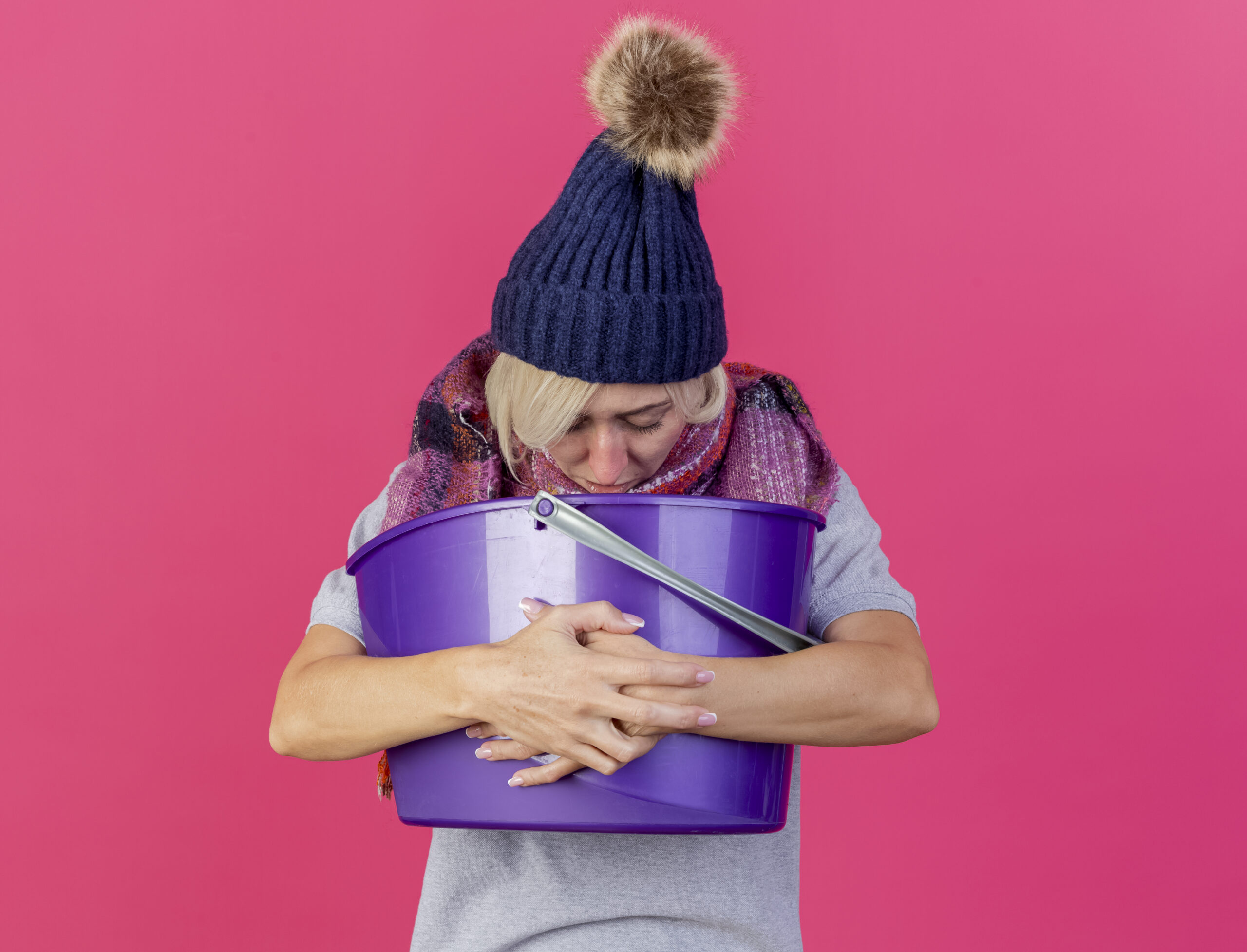 A woman holding a bucket and puking due to lactose intolerance.