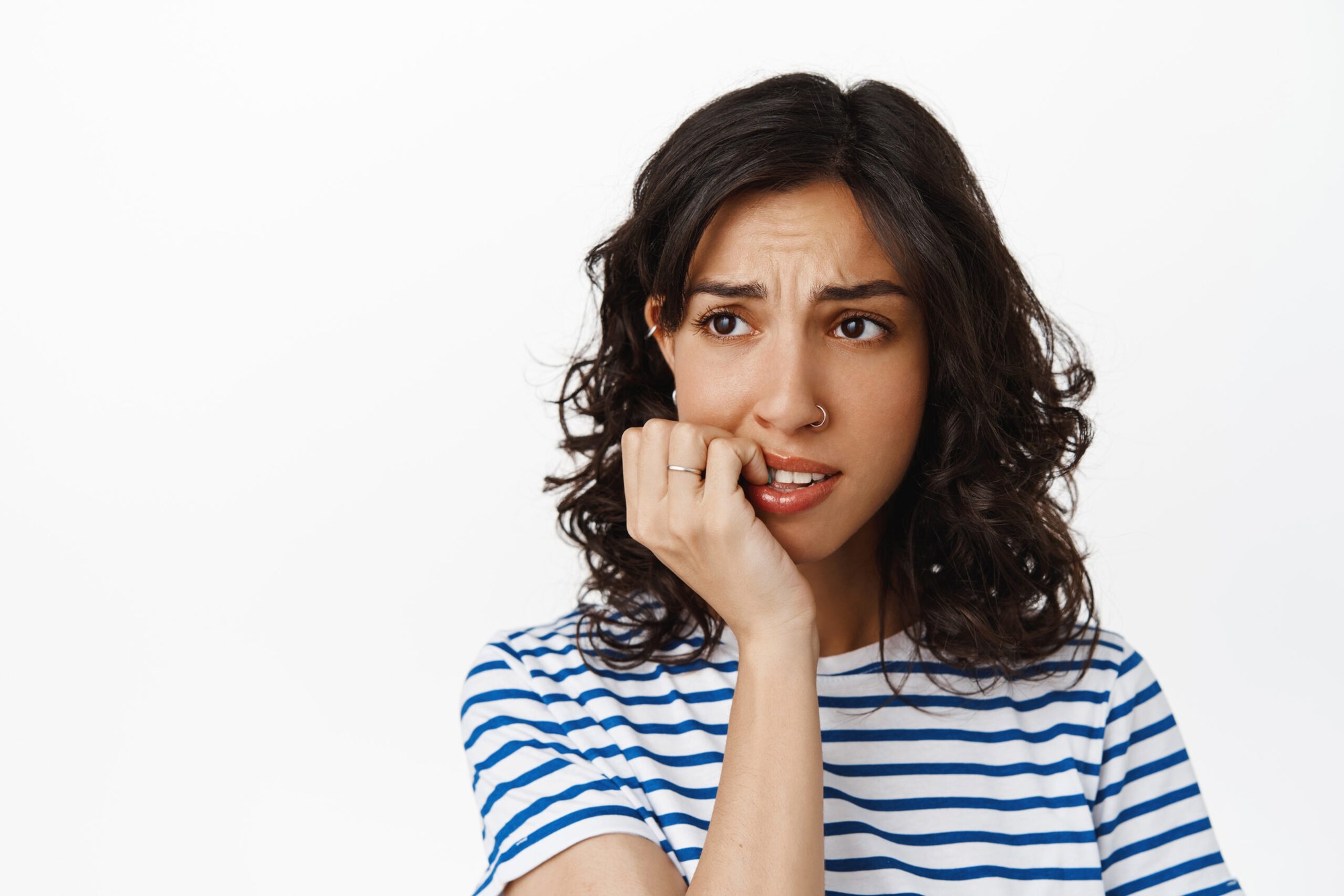 Close-up of a woman biting her finger in stress, symbolizing how anxiety and stress contribute to premature aging.