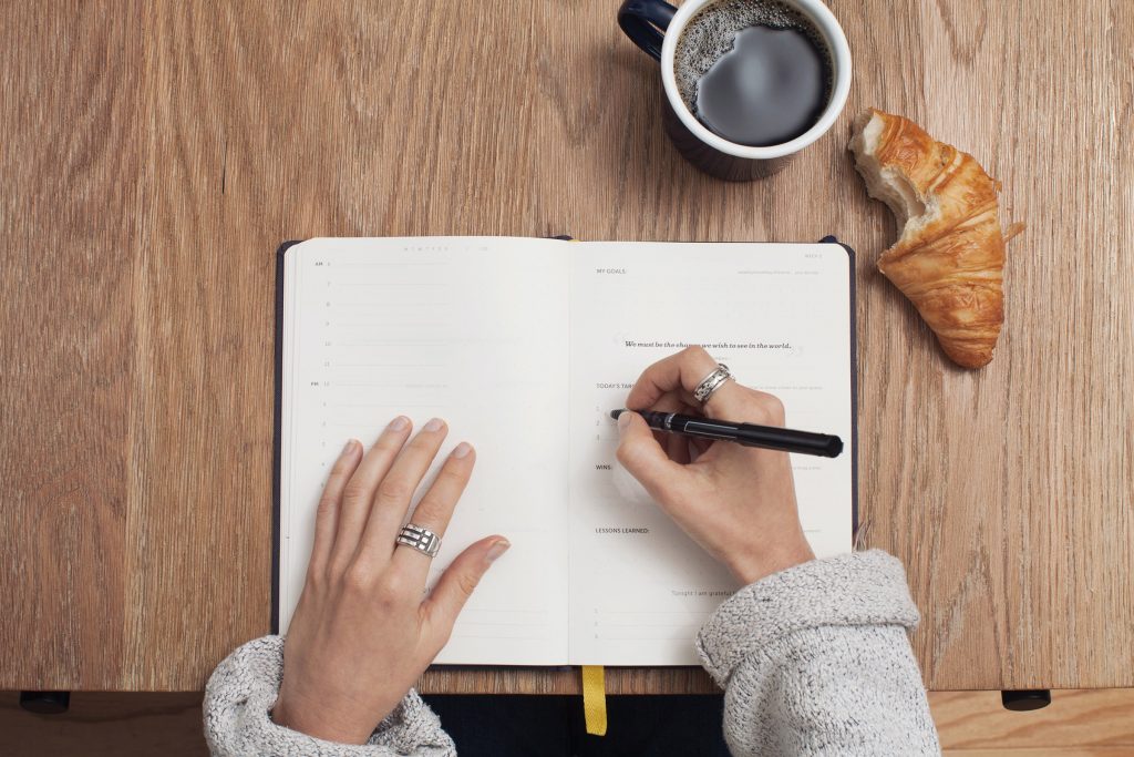 A woman writing in a food journal, highlighting its importance in her health journey."