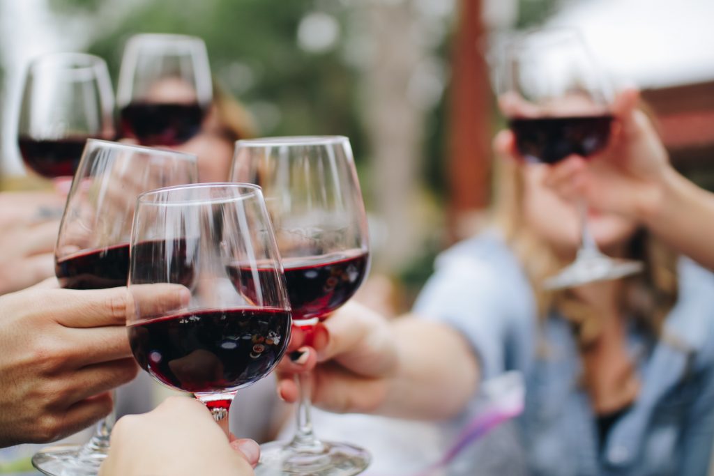 A close-up shot of people clinking glasses of alcohol, celebrating together.