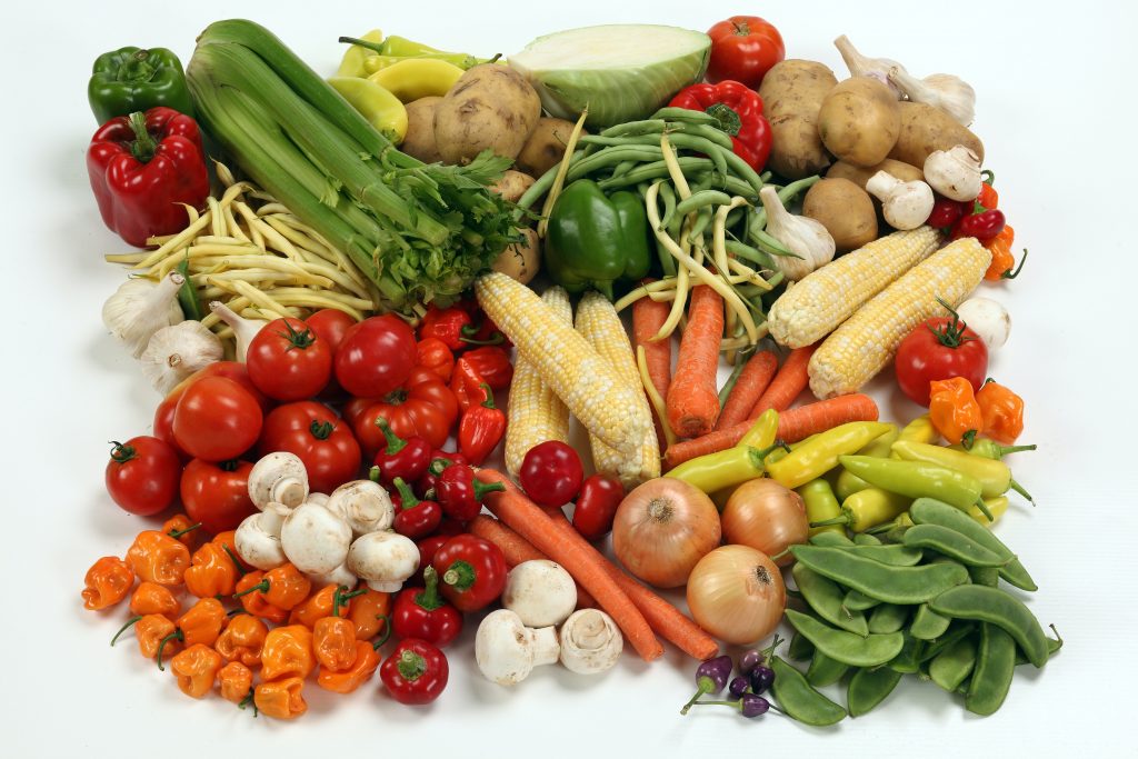 Top view of assorted vegetables including beans, onions, peppers, cabbage, potatoes, mushrooms, chilies, and lettuce.
