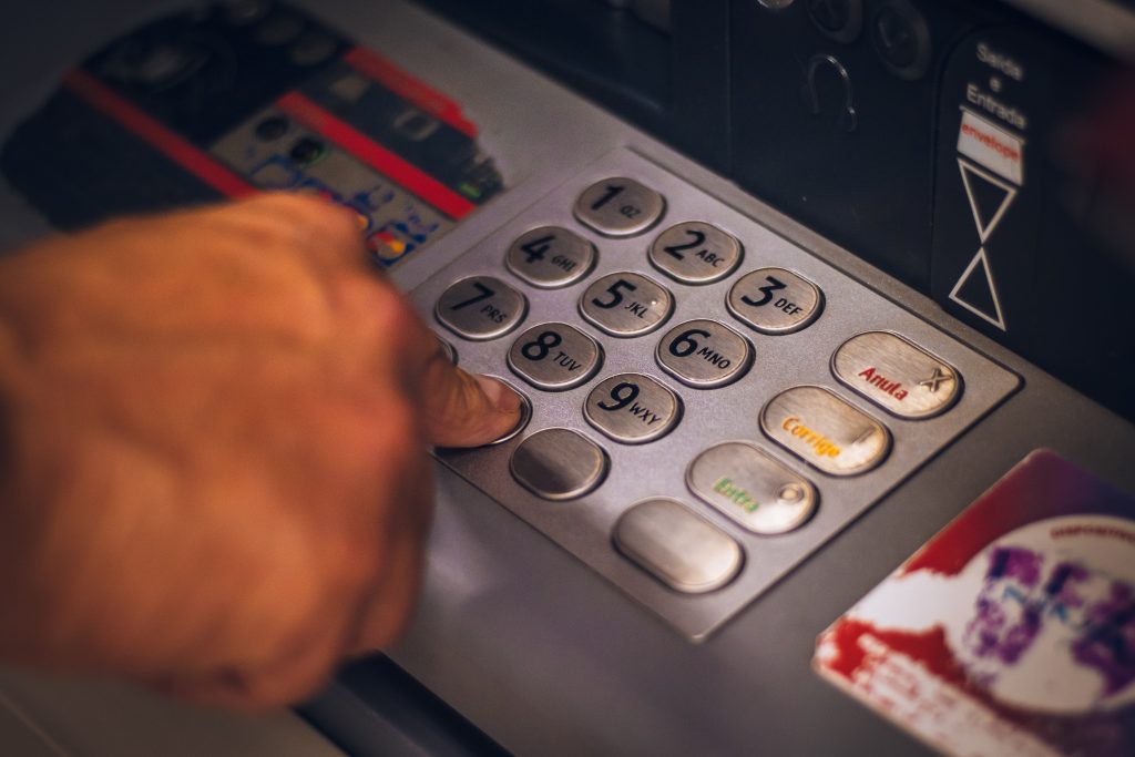 A close-up shot of a person pressing the keypad of an ATM machine.
