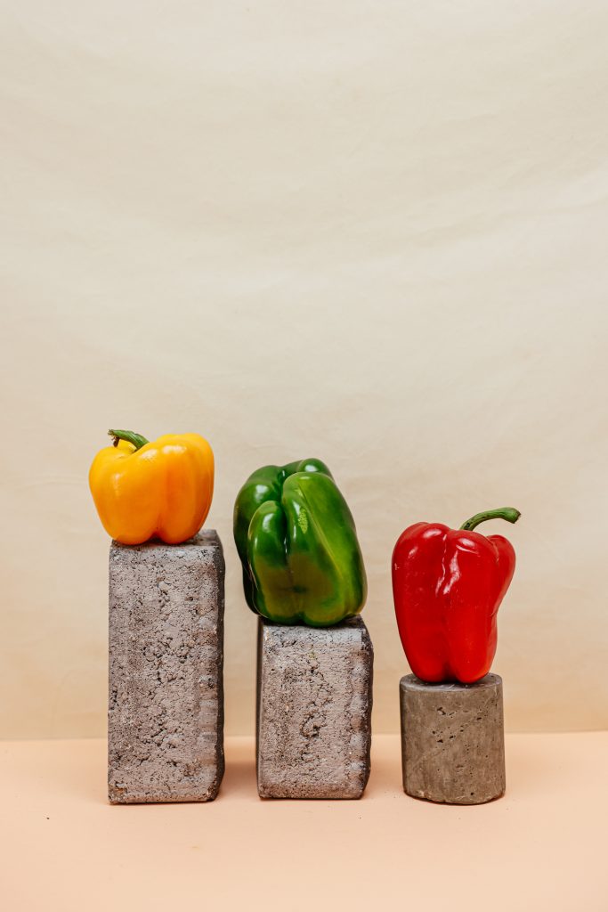 Bell peppers in three different colors placed over stones of varying sizes, creating a vibrant and natural display.