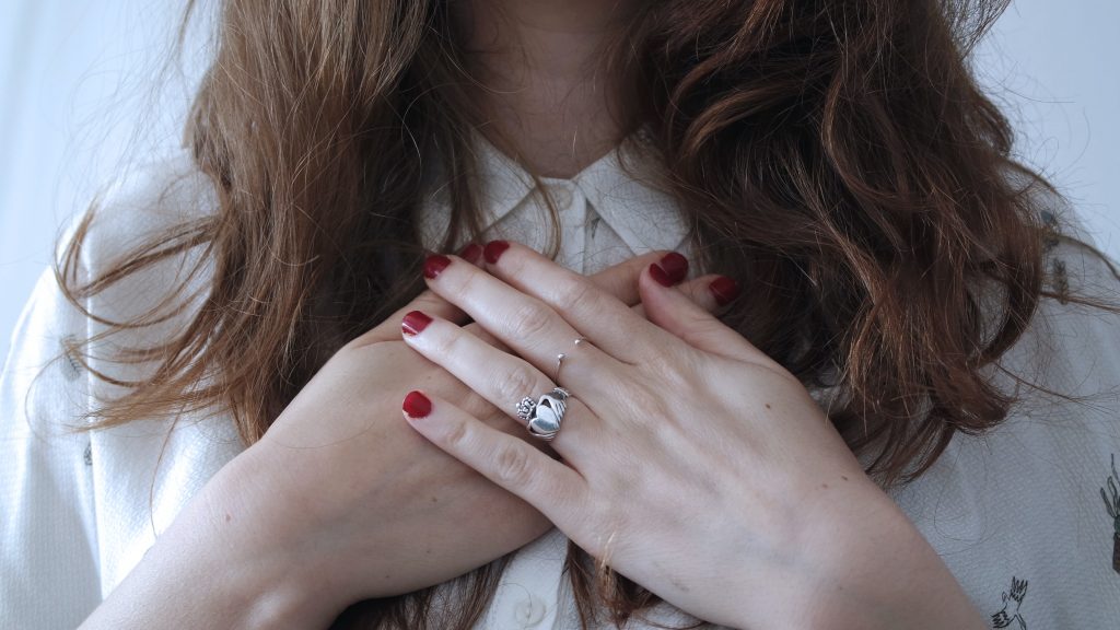 A woman holding her chest, as anxiety disorders can lead to rapid heart rate, palpitations, and chest pain.