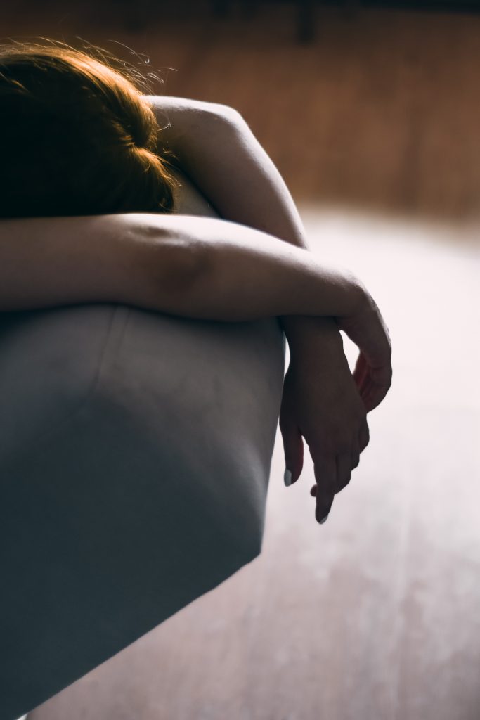 A young girl lying on a couch, appearing fatigued.