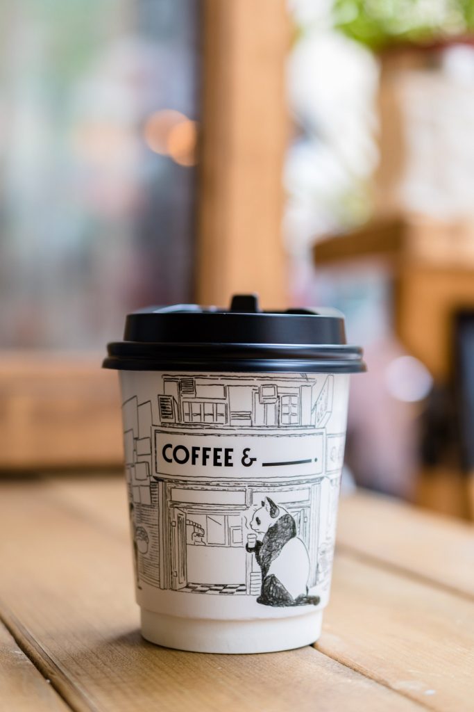 A close-up shot of a disposable takeout coffee cup placed on a wooden table.
