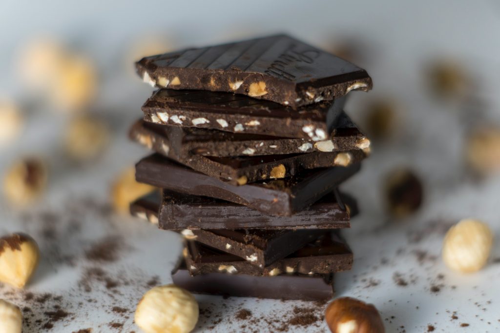 A close-up shot of hazelnut dark chocolate pieces stacked vertically, showcasing their rich texture and nutty goodness.