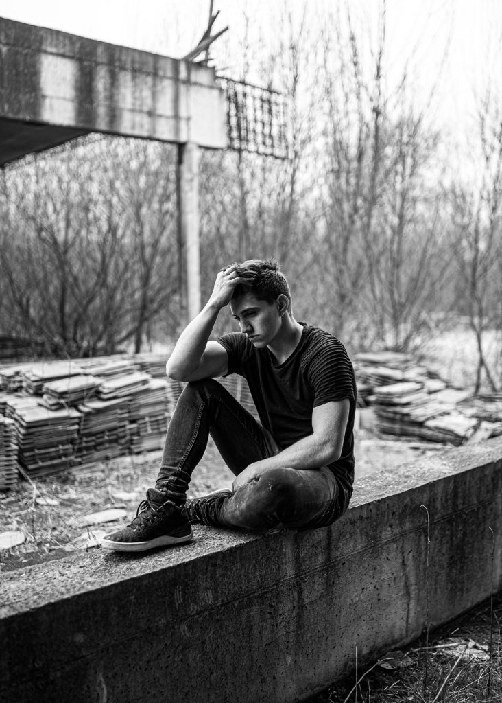 A black and white image of a young man appearing depressed, highlighting how a diet high in sugar and processed foods can increase depression risk.