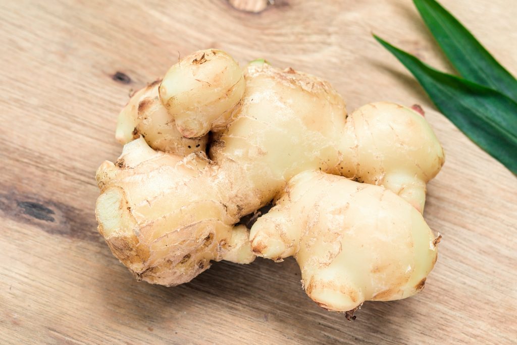 A close-up shot of thoroughly washed fresh ginger placed on a wooden surface