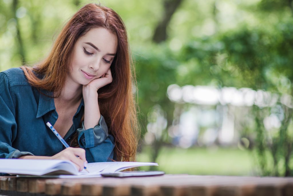 A woman jotting down in a journal, an easy and effective way to reduce stress.