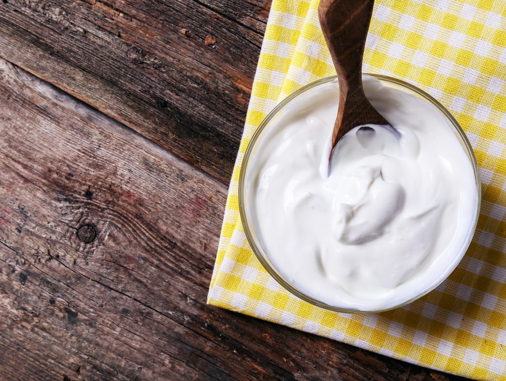 A bowl of Greek yogurt placed on a wooden table.
