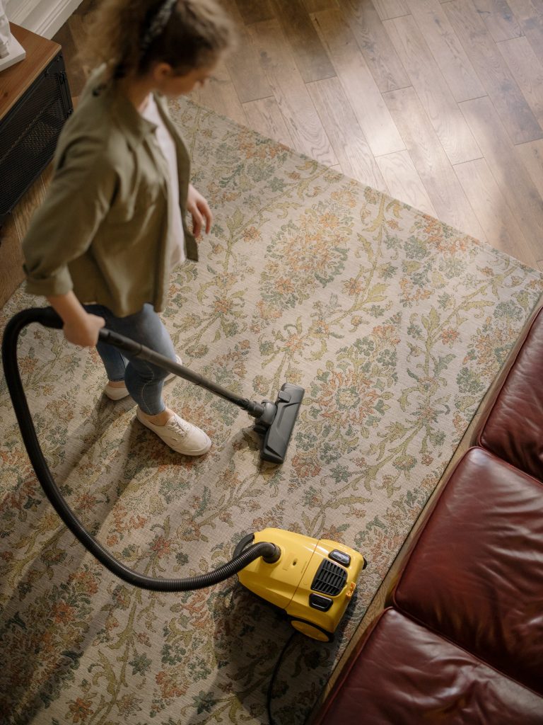 A young woman cleaning the home with a vacuum cleaner.