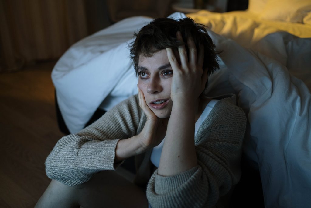 A tired woman unable to sleep, watching TV late at night.