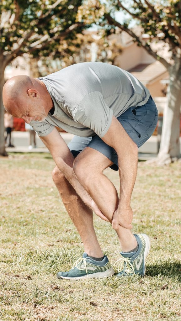 A man holding his lower leg, suffering from severe joint pain.