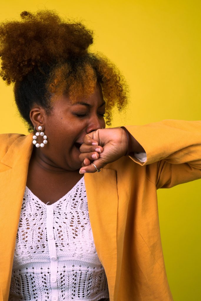 A woman dressed in formals yawning, indicating low energy levels and fatigue.