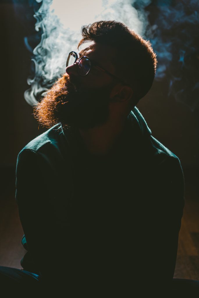 A candid shot of a young man relaxing while smoking, depicting casual use.