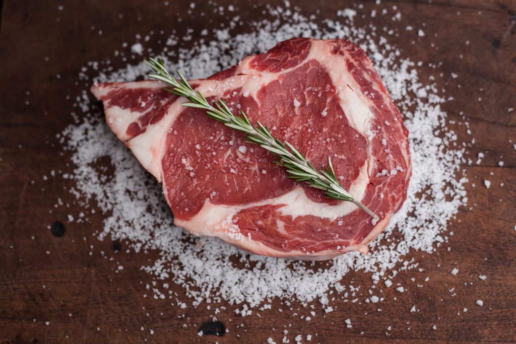 Raw thin slice of beef garnished with herbs and salt, illustrating its benefits for eye health.